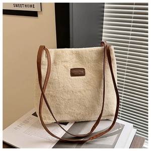 Détail d'un sac fourre-tout en peluche crème avec écusson en cuir marron et lanière