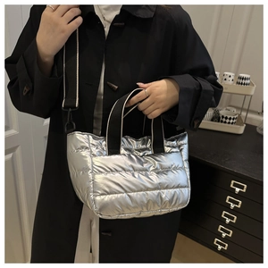 Detail der silbernen Metallic-Stepptasche mit schwarzem Nylon-Griff und Schultergurt