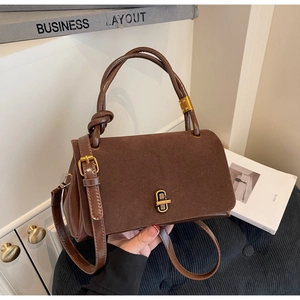 Detail of suede crossbody bag with vintage gold metal clasp and knotted handle