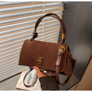 Detail of brown suede and leather splicing texture with a golden twist lock closure