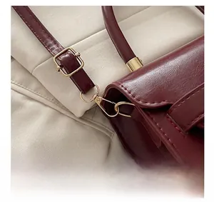 Dettaglio della texture della pelle bordeaux e degli accessori metallici dorati della borsa