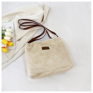 Détail du sac fourre-tout en peluche crème avec bandoulière en cuir marron et étiquette mode