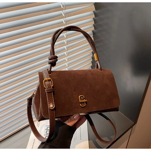 Detail of suede crossbody bag featuring a vintage gold rectangular twist lock closure