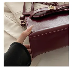 Dettagli di cuciture precise e chiusura in metallo dorato su borsa in pelle bordeaux