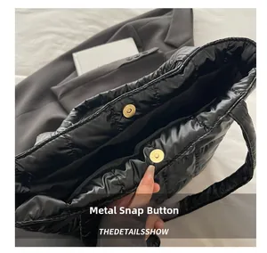 Detail of the high-quality magnetic snap closure on a black quilted down tote bag