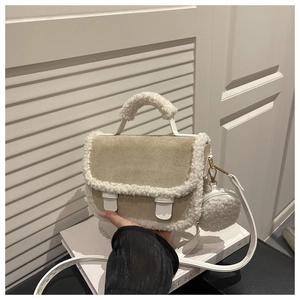 Detail of beige suede handbag with white faux shearling trim and round coin purse charm