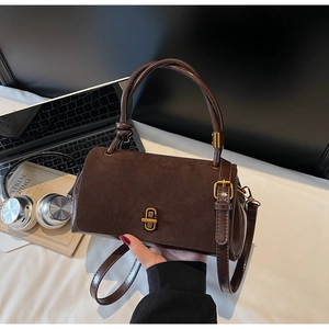 Detailed view of suede shoulder bag with golden lock on office desk workspace
