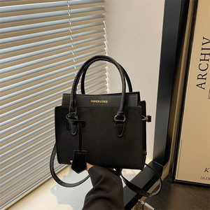 Minimalist black large capacity leather tote bag with gold lettering shown in a studio setting
