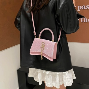 Pink sequin crossbody bag with gold logo and wavy bottom shown on fashion model