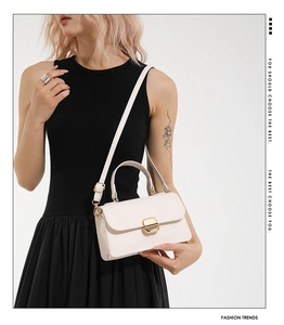 Detail of minimalist cream square bag with gold lock and adjustable shoulder strap