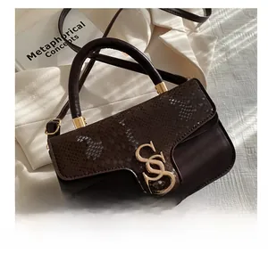 Detail van donkerbruine retro handtas met slangenprint textuur en gouden metalen gesp