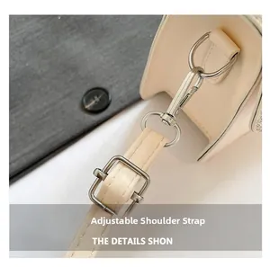 Detail view of cream PU leather handbag with adjustable shoulder strap and silver buckles