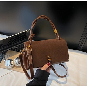 Detail view of brown faux suede handbag with decorative twisted handle and gold clasp