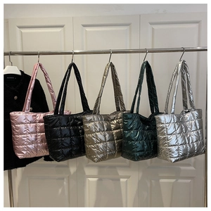 Detailed row of quilted puffer tote bags in five metallic colors on a silver hanger