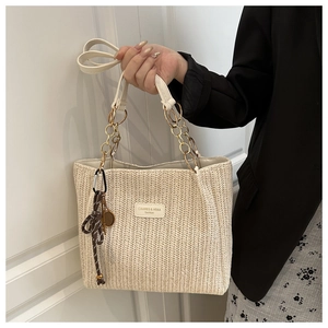 Detailed V-pattern straw weave on a beige tote with chain strap and tennis racket charm