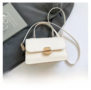 Detailed shot of a beige small square bag featuring a gold metal twist lock on a grey fabric