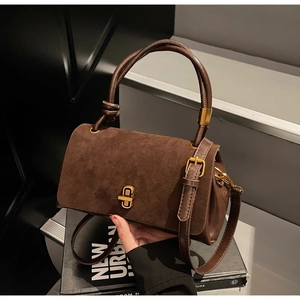 Detail of brown faux suede handbag with vintage gold metal twist lock and leather handle