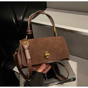 Detail of vintage brown suede stitching handbag with U-shaped gold metal lock and strap