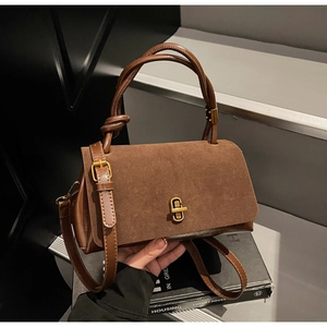 Detailed view of brown suede handbag with golden metal twist lock and knotted top handle