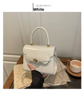 Detailed close-up of white leather handbag with golden twist lock and round handle