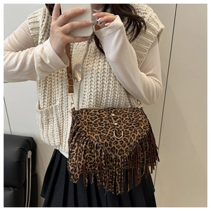 Detail of bohemian leopard print saddle bag featuring long fringe and gold hardware