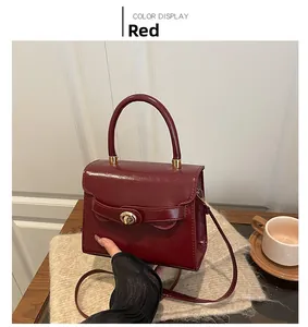 Detail of red faux leather handbag featuring a vintage metal twist lock and top handle
