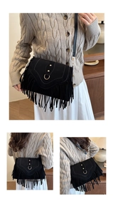 Detail of bohemian black suede crossbody bag with fringe and golden horseshoe buckle