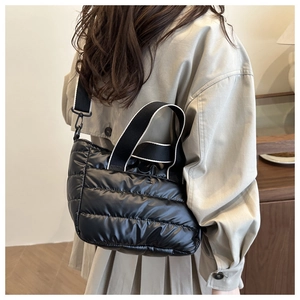 Detalle de bolso tote acolchado negro con asas anchas y correa de hombro ajustable
