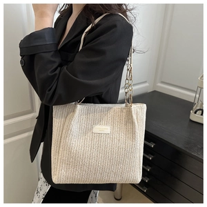 Detail of woven straw tote bag with chain strap and elegant chevron textured finish
