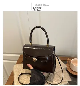 Detail of coffee brown glossy faux leather handbag with golden twist lock and top handle