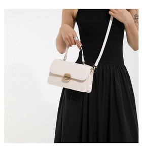 Detailed view of a white leather crossbody bag with a golden metallic rectangle lock buckle