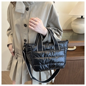 Detalle del bolso acolchado negro con elegantes asas tejidas a rayas blancas y negras