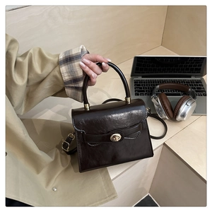 Dettaglio di una borsa a mano vintage marrone scuro con chiusura dorata su scale in legno