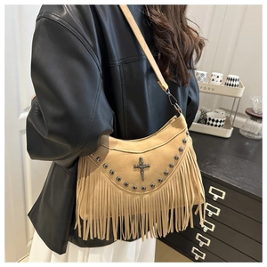 Dettaglio borsa a spalla boho in camoscio con borchie metalliche, ciondolo a croce e frange