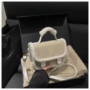 Detail of suede crossbody bag with plush faux shearling trim and golden hardware