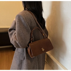 Detail of dark brown faux suede handbag featuring elegant glossy leather trim and twist lock