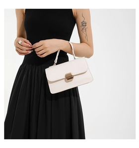 Close-up of white leather handbag with elegant gold square rotating lock and handle