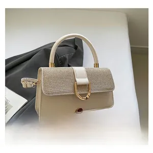 Detail of elegant cream handbag featuring glitter panel and golden D-ring buckle hardware
