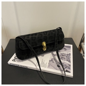 Dettaglio borsa baguette nera maculata con chiusura cilindrica in metallo dorato