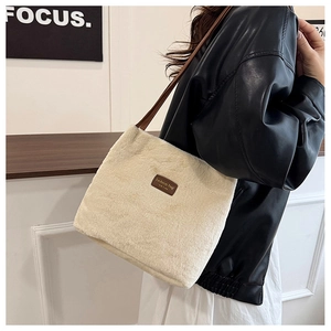 Détail d'un sac cabas en peluche crème avec étiquette en cuir marron et bandoulière