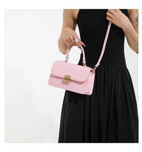 Detail of pink leather handbag with gold metal twist lock and detachable shoulder strap