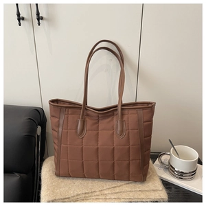 Detail of chocolate brown quilted tote bag with stitched grid pattern and leather handle