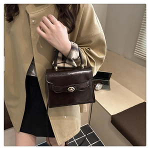Deep brown vintage square bag with metal turn-lock and top handle on a model