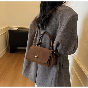 Brown suede crossbody bag with vintage gold lock worn with a grey wool coat