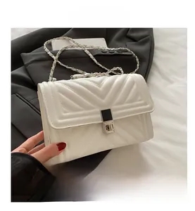 Detail of white quilted chain bag featuring V-shaped stitching and metal buckle