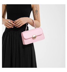 Detailed view of a pink leather crossbody bag with a gold lock and metal buckle details