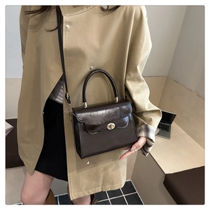 Fashionable dark brown glossy leather handbag worn with a chic autumn trench coat