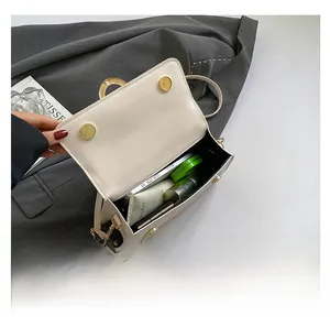 Detail view of cream white flap bag interior showing capacity with phone and cosmetics