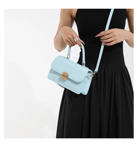 Detail of light blue leather handbag featuring gold metal buckle and matching shoulder strap