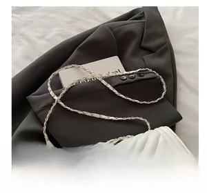 Close-up of white quilted crossbody bag showing V-pattern stitching and gold chain strap
